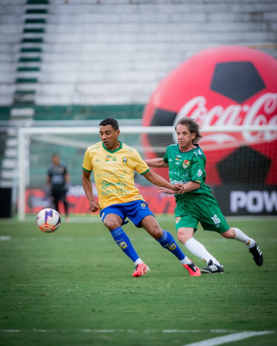 Jogadores disputando a bola diante do gol no estádio Tahuichi